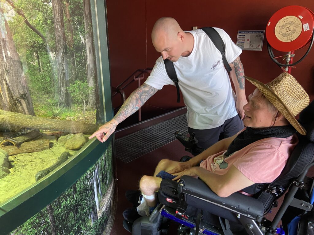 Louis support worker with client, pointing at fish in tank